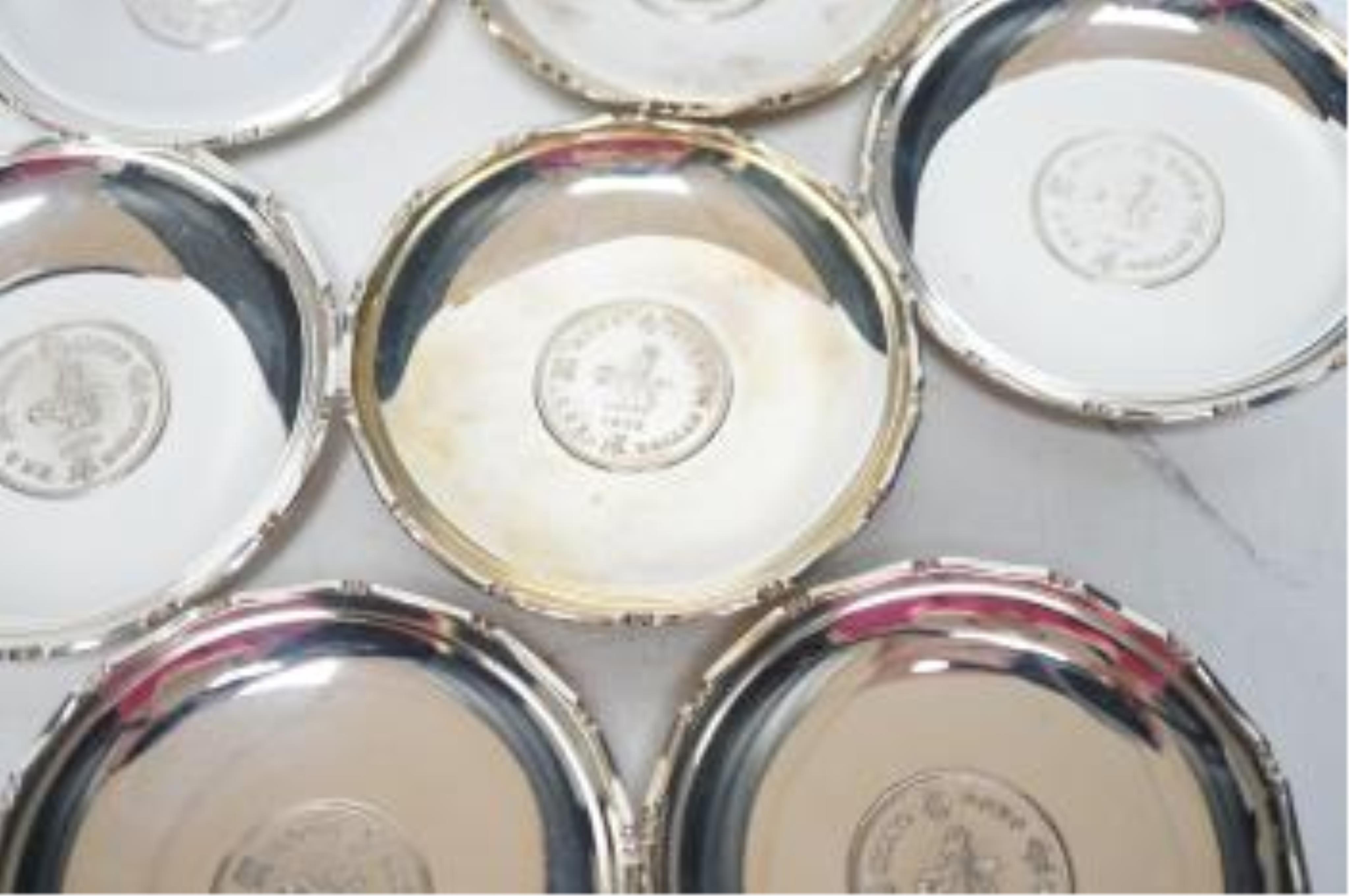 A set of seven Hong Kong sterling small dishes with inset coin, signed 'Sammy', diameter 86mm, gross weight 10.2oz. Good condition.